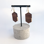 Back view of wooden earrings hanging on a stand, showing the raw walnut finish and earring construction.