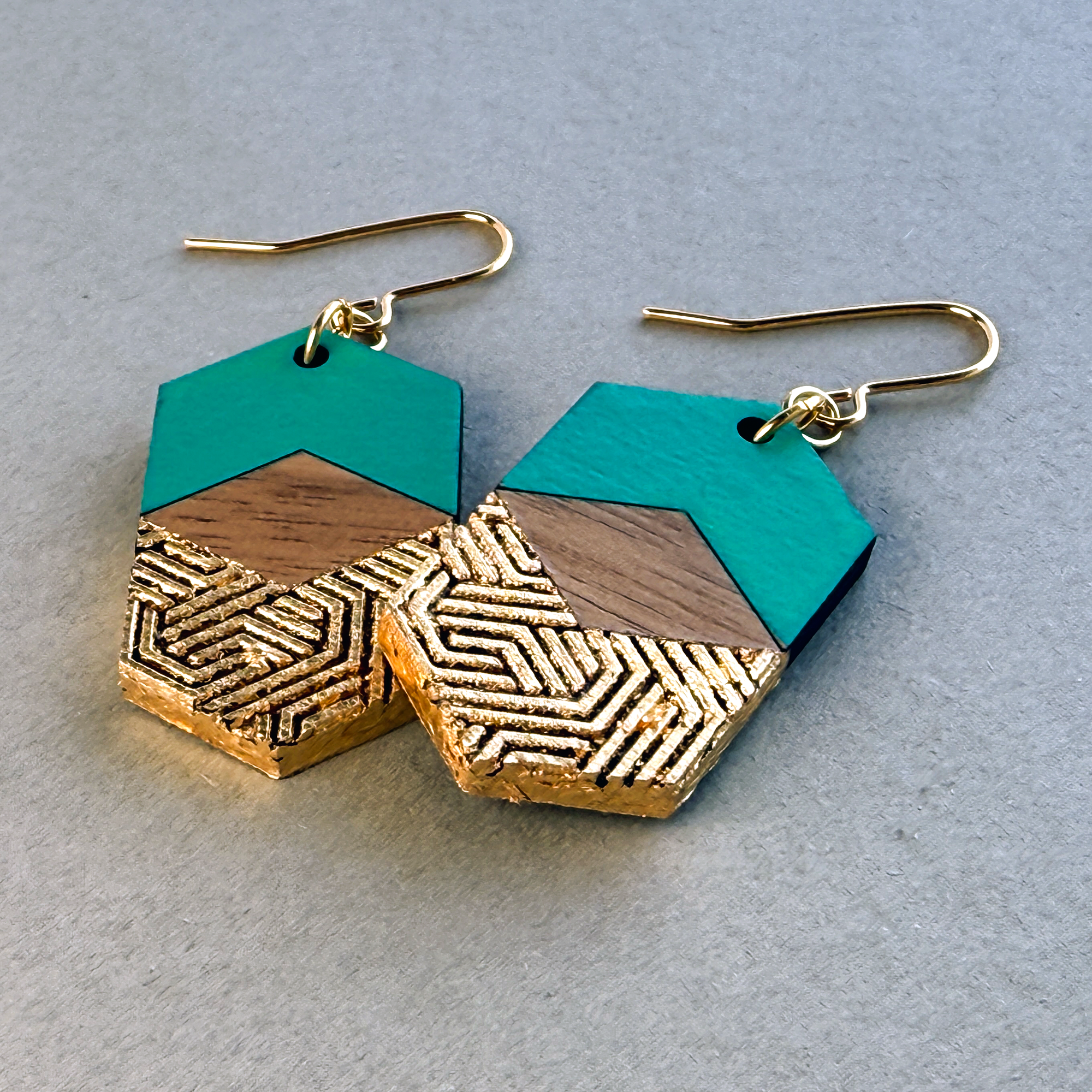 Pair of handcrafted hexagonal earrings laid flat on a neutral grey background, showing shape and colour.