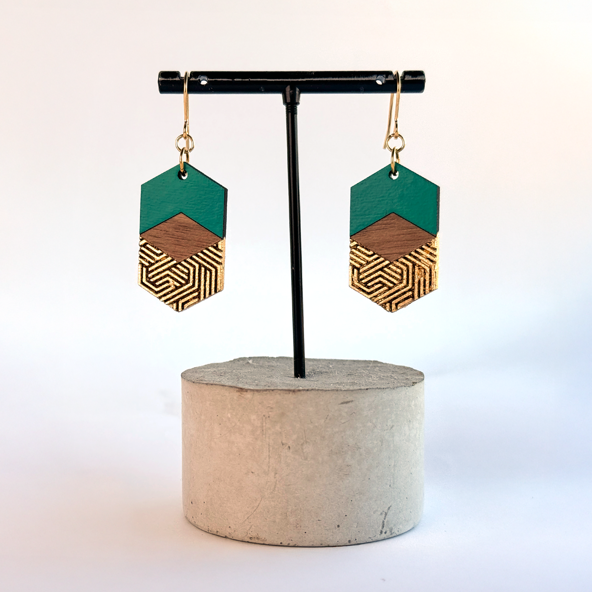 Earrings displayed hanging on a concrete stand, showing how they fall naturally when worn.